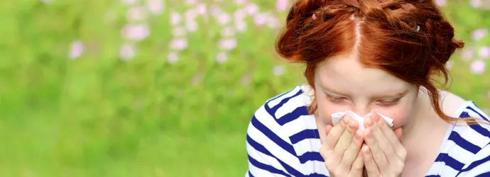 donna dai capelli rossi con camicetta a righe piange con una sciarpa sul viso