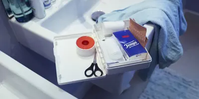 EHBO-kit in de wastafel, met Tempo-tissues, een schaar en andere basisbenodigdheden.