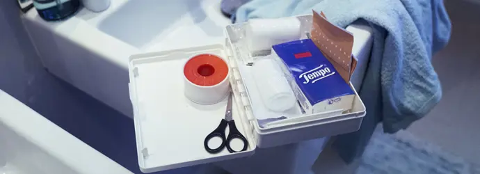 EHBO-kit in de wastafel, met Tempo-tissues, een schaar en andere basisbenodigdheden.