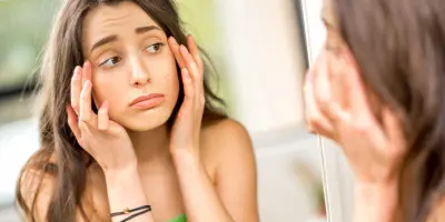 Ein Teenager überprüft von einer Allergie geschwollene Augen in einem Spiegel
