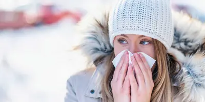 Eine Frau im Schnee schneuzt sich