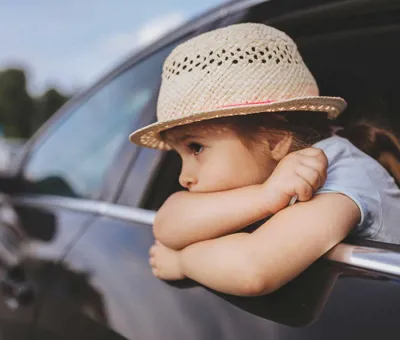 Ein Kind, dem beim Autofarhen übel geworden ist lehnt sich aus dem Autofenster