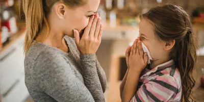 Eine Mutter zeigt ihrer Tochter, wie sie Nasenbluten stoppen kann
