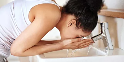 Eine Frau spült ihr Gesicht in einem Waschbecken