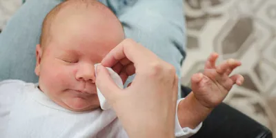 Ein Elternteil reinigt die verklepten Augen eines Babys