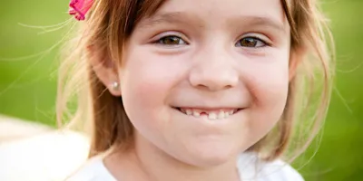Een jong meisje lacht en laat het gat tussen haar tanden zien, waar haar melktandje net nog kan zijn geweest