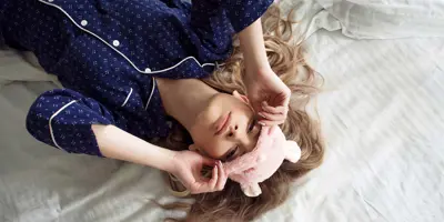 Een kind dat 's nachts een verstopte neus heeft ligt in bed met een oogmasker