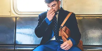 Een man draagt een pak in een treinwagon en snuit zijn neus