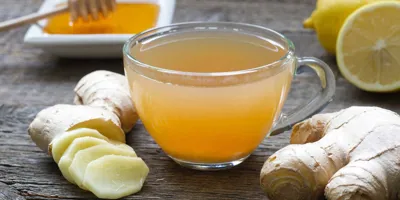 Hele en gehakte gember, honing, citroen en een glas met het mengsel staan op een houten tafel