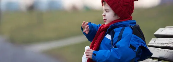 Ein Kind niest auf einer Parkbank im Winter