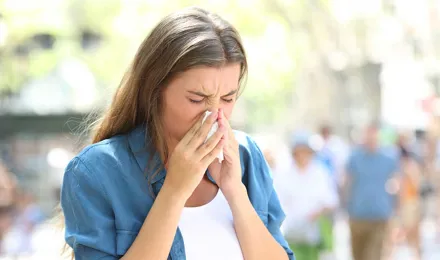 Eine Frau mit Erkältung im Sommer putzt sich die Nase
