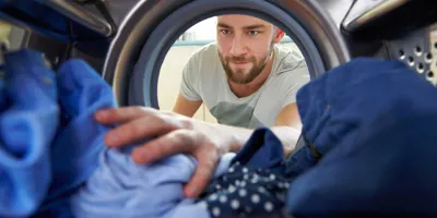 Man reikt naar kleding in de wasmachine