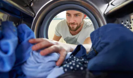 Man reikt naar kleding in de wasmachine