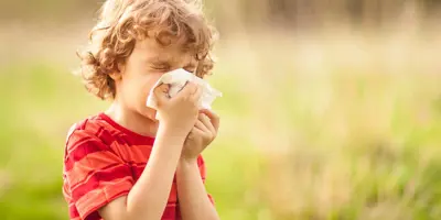 Een jongen met een pollenallergie snuit zijn neus buiten in een veld