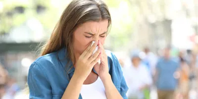 Vrouw met verkoudheid in de zomer snuit haar neus