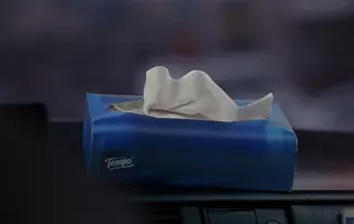Foto van een blauwe Tempo-tissuebox op het matzwarte dashboard van een taxi