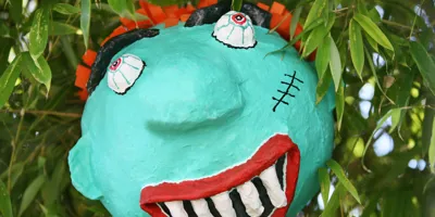 Eine gruselige selbst gebastelte Halloween-Piñata eines Monsters, die in einem Baum hängt.