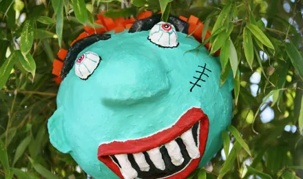 Eine gruselige selbst gebastelte Halloween-Piñata eines Monsters, die in einem Baum hängt.