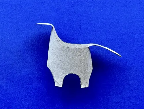 Rotolo di carta igienica a cui è stata data la forma di un piccolo dinosauro giace su sfondo viola.