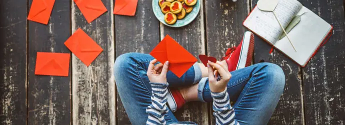 Eine Frau sitzt auf dem Boden und schreibt Karten als selbstgemachtes Geschenk für Valentinstag