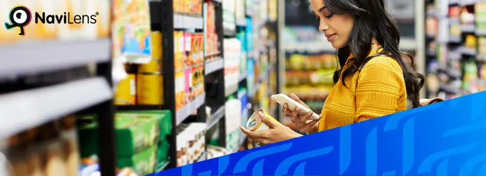 Una donna che indossa una camicia gialla e scansiona un codice QR di un prodotto in un supermercato. Agli angoli opposti della foto figurano i loghi Tempo e NaviLens
