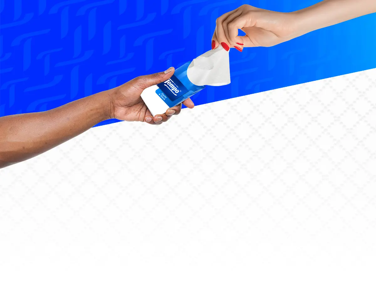 Twee handen wisselen een pakje Tempo-tissues uit tegen een blauwe achtergrond