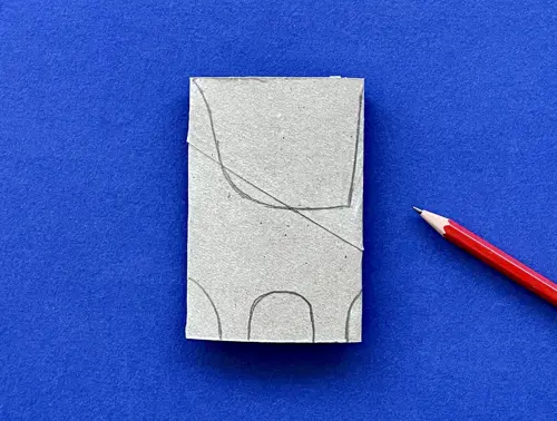 Rotolo di carta igienica schiacciato su cui è disegnato il profilo di un dinosauro e accanto una matita, tutto su sfondo blu.