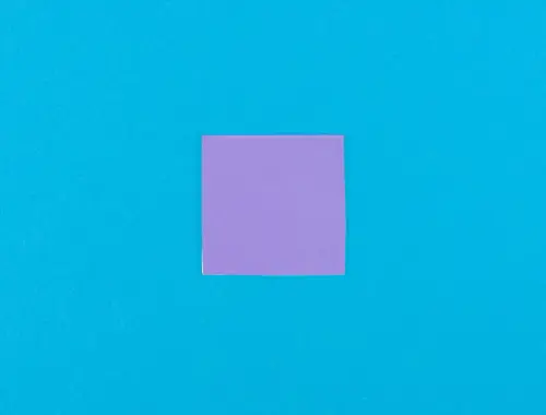 Foglio quadrato color viola giace su sfondo blu.