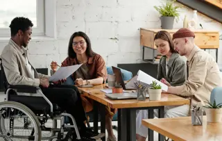 Un gruppo di colleghi, tra cui una persona in sedia a rotelle, collabora in un ufficio.