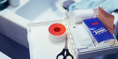 Cassetta di pronto soccorso nel lavabo, con fazzoletti, forbici e altri articoli di base.