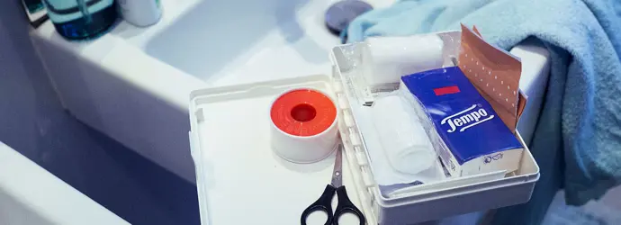 Cassetta di pronto soccorso nel lavabo, con fazzoletti, forbici e altri articoli di base.