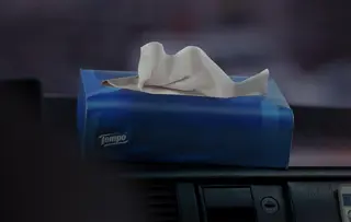 Foto einer blauen Tempo Taschentücher Box auf dem mattschwarzen Armaturenbrett eines Taxis