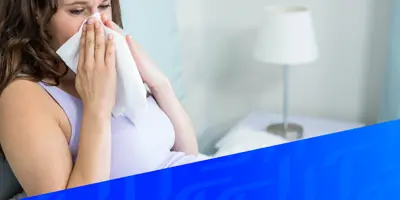 Afbeelding van een vrouw die in bed haar neus zit te snuiten, met daaroverheen een diagonaal blauw Tempo-patroon in de rechterhoek.