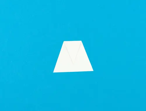 Un ritaglio di carta bianca a forma di trapezio giace su uno sfondo blu.