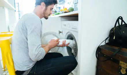 Ein Mann legt Kleidung in eine Waschmaschine