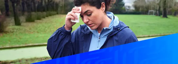 Afbeelding van een vrouw die haar bezwete voorhoofd afveegt over een diagonaal Tempo blauw patroon in de rechterhoek.