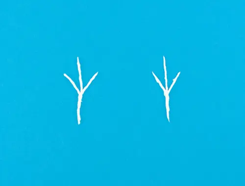 Due pezzetti di carta bianchi intrecciati a cui è stata data la forma di orecchie da renna su sfondo blu.