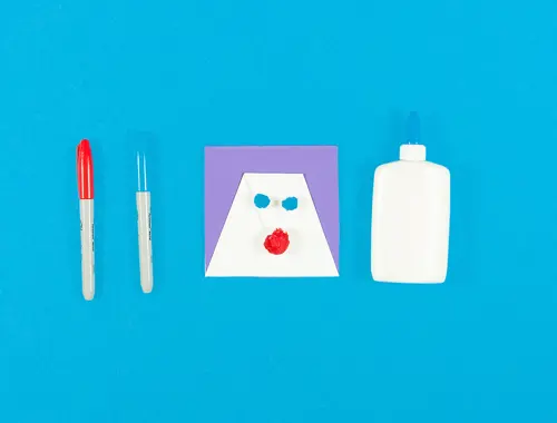 Un ritaglio al centro richiama il volo di una renna con accanto due pennarelli colorati e un contenitore di plastica bianco.