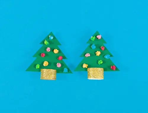 Due alberi di Natale fatti con carta verde, foglietti di carta colorata per decorazioni e nastro glitterato oro su sfondo blu