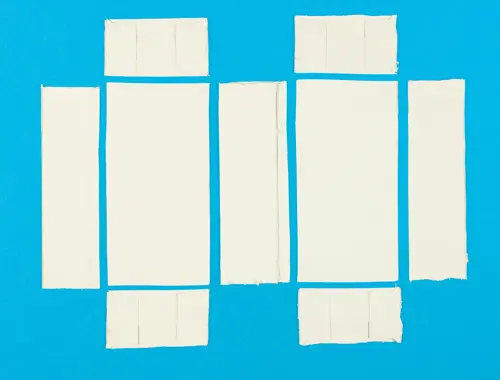 Ritagli di carta color crema di forma rettangolare di diversa dimensione posti in ordine su sfondo blu.