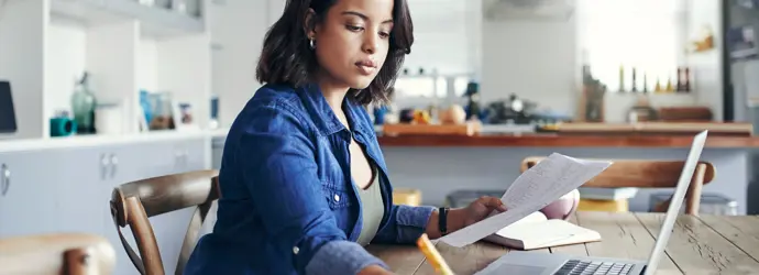 Una donna siede al computer in una stanza luminosa e appare concentrata nel suo lavoro.