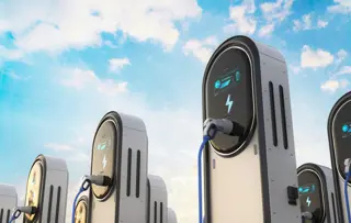 Moderne stazioni di ricarica per veicoli elettrici sotto un cielo azzurro e limpido.